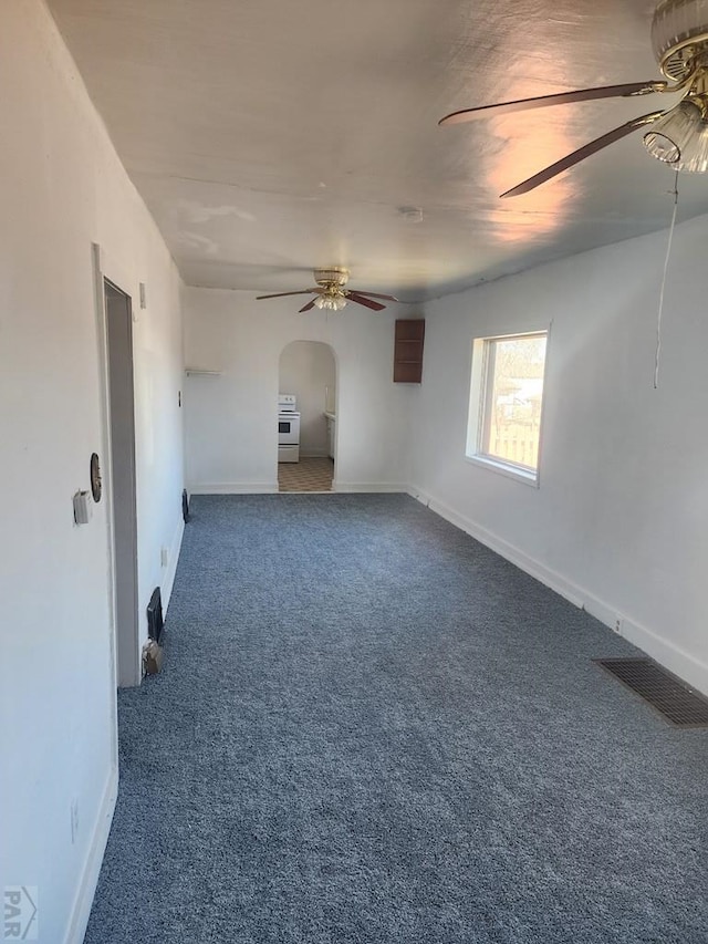 carpeted spare room featuring arched walkways, baseboards, visible vents, and a ceiling fan