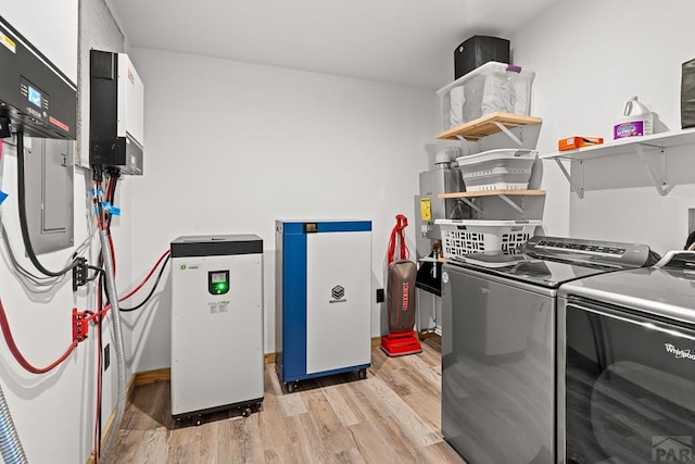 clothes washing area with laundry area, washer and clothes dryer, and light wood-style floors