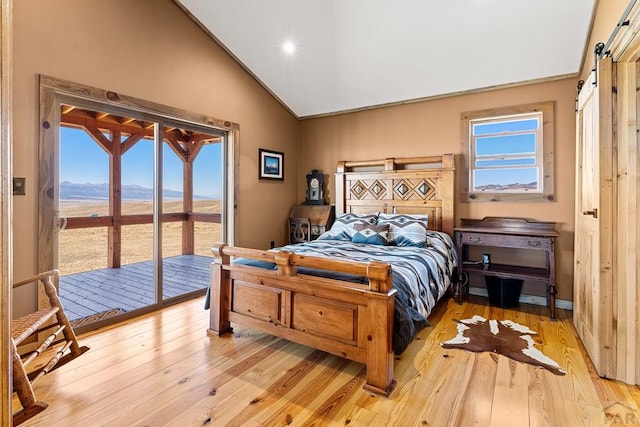 bedroom with lofted ceiling, a barn door, a mountain view, access to exterior, and light wood finished floors