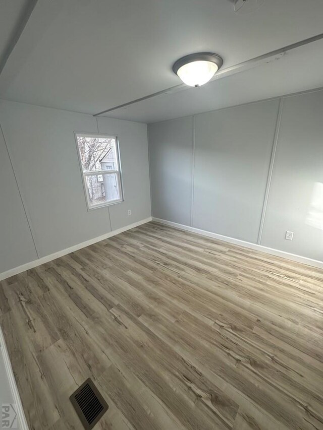 unfurnished room with light wood finished floors, baseboards, and visible vents