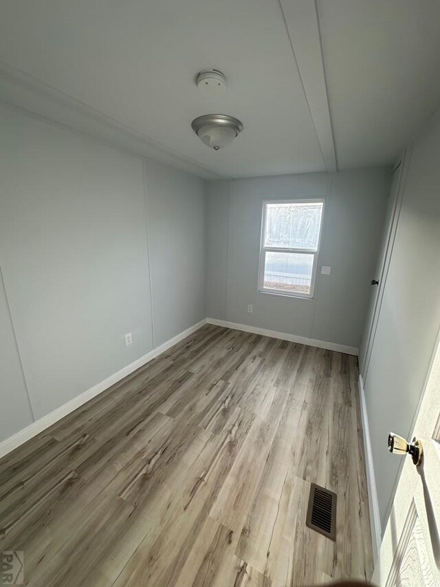 unfurnished room featuring light wood-style flooring, visible vents, and baseboards