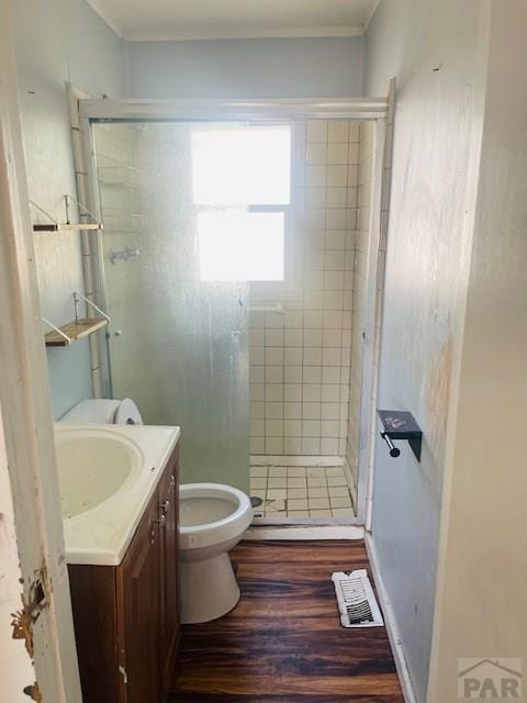 bathroom with toilet, wood finished floors, visible vents, vanity, and a stall shower