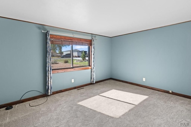 empty room with carpet floors, ornamental molding, and baseboards