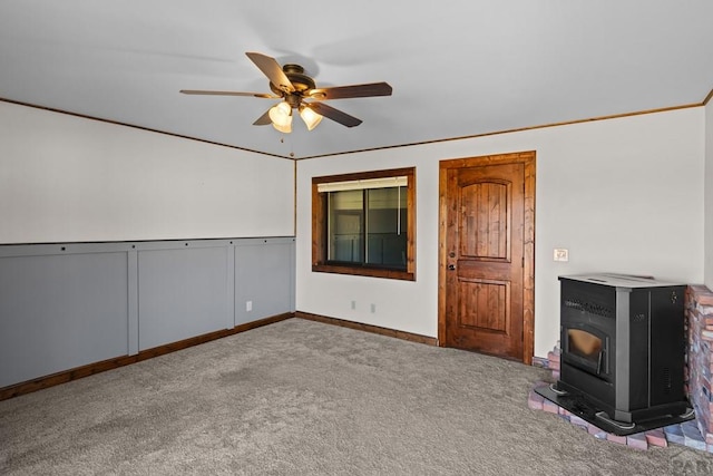 unfurnished living room featuring carpet floors, a wood stove, a ceiling fan, and baseboards