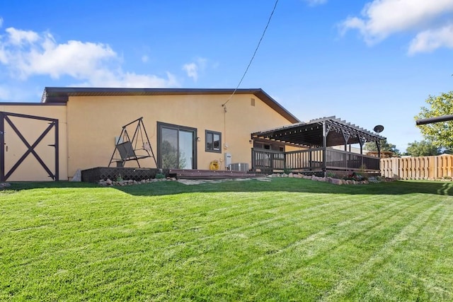 rear view of house featuring stucco siding, a yard, fence, and a pergola