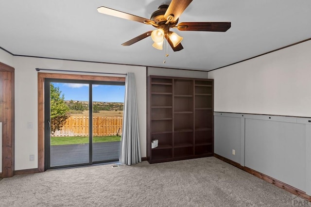 empty room with baseboards, visible vents, a ceiling fan, light colored carpet, and ornamental molding