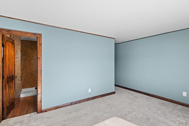 unfurnished room featuring dark carpet and baseboards