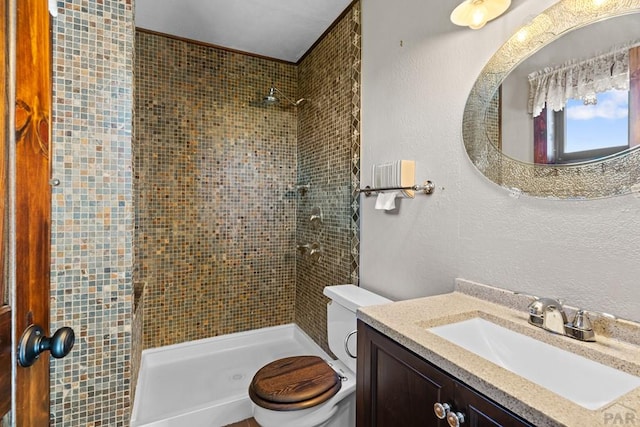 bathroom featuring toilet, a textured wall, a shower stall, and vanity