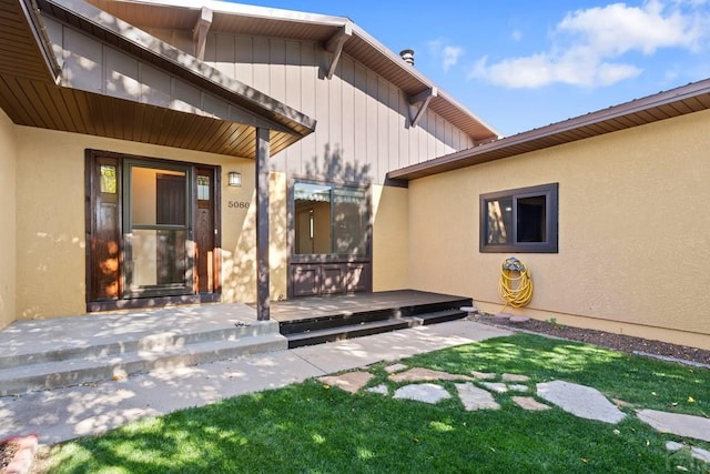 rear view of house featuring a deck, a lawn, and stucco siding