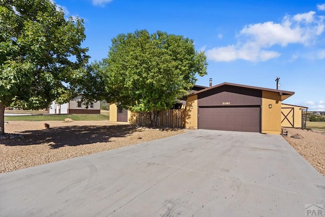 view of front of property featuring a garage, concrete driveway, and fence