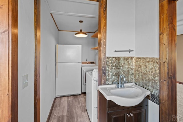 kitchen with a sink, light countertops, freestanding refrigerator, washer / clothes dryer, and pendant lighting