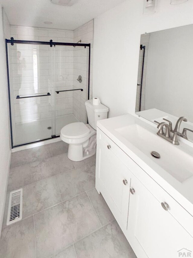 bathroom featuring vanity, toilet, visible vents, and a stall shower
