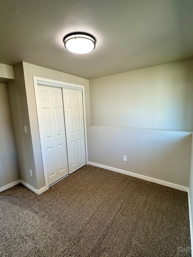 3923 Lancaster Dr, Pueblo, CO 81005 - unfurnished bedroom with dark carpet, a closet, and a textured ceiling