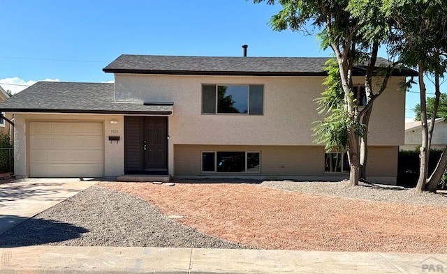 3923 Lancaster Dr, Pueblo, CO 81005 - split level home featuring concrete driveway, a garage, a shingled roof, and stucco siding