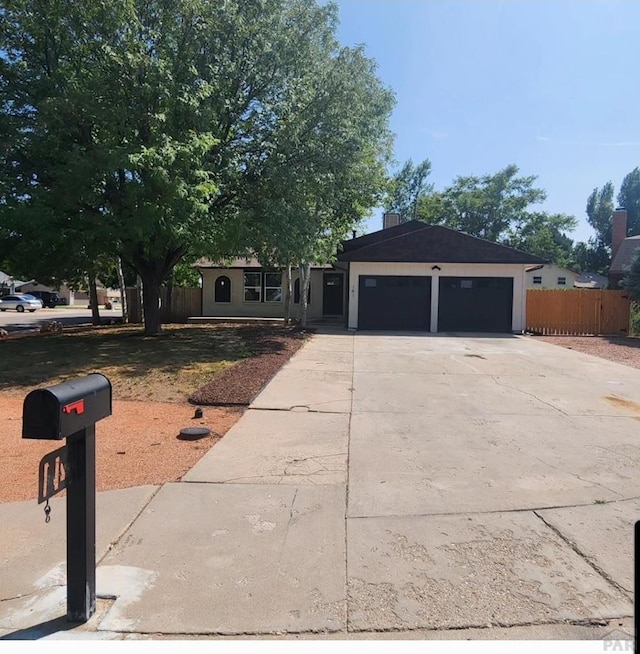 ranch-style home with a garage, fence, and driveway