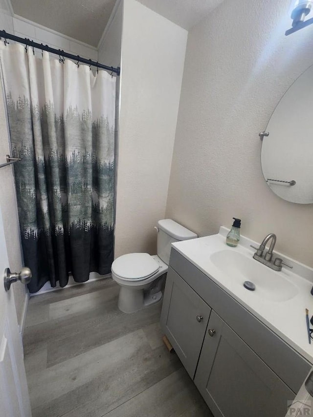 bathroom with toilet, a shower with curtain, wood finished floors, and vanity