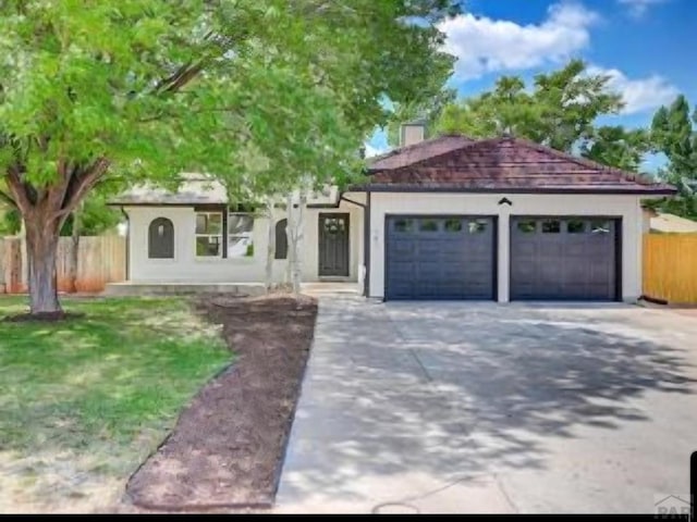 mediterranean / spanish home featuring a garage, driveway, a chimney, and fence