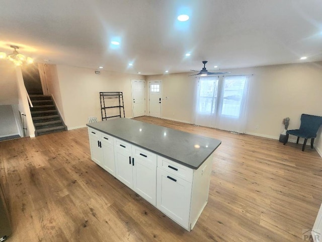 kitchen featuring dark countertops, open floor plan, white cabinetry, and light wood-style flooring