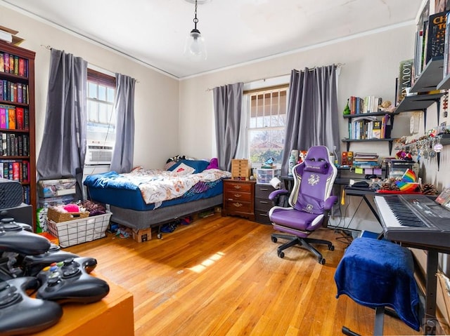 bedroom with multiple windows, cooling unit, wood finished floors, and ornamental molding