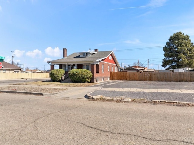 view of front of property with a chimney, fence, and brick siding