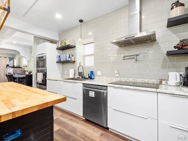 kitchen featuring appliances with stainless steel finishes, a sink, wall chimney exhaust hood, and open shelves