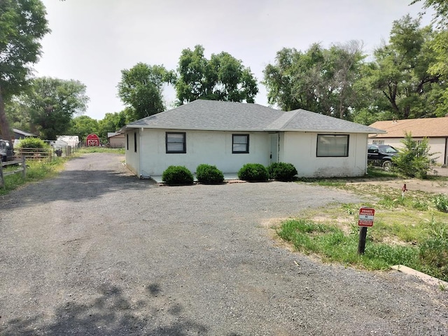 1143 25th Ln, Pueblo, CO 81006 - view of front facade with gravel driveway, stucco siding, and roof with shingles