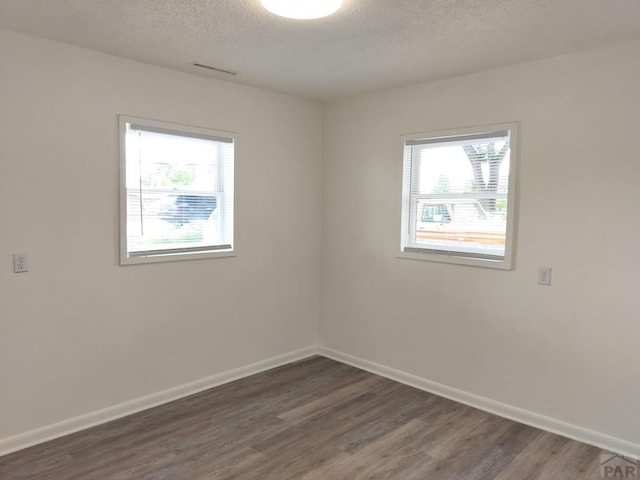 1143 25th Ln, Pueblo, CO 81006 - unfurnished room with plenty of natural light, a textured ceiling, wood finished floors, and baseboards