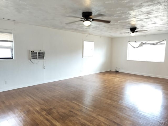 1143 25th Ln, Pueblo, CO 81006 - unfurnished room featuring a wall unit AC, ceiling fan, wood finished floors, and baseboards