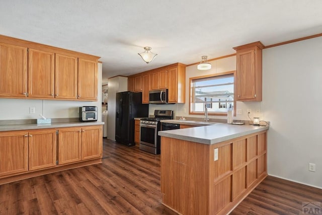 kitchen featuring stainless steel appliances, light countertops, dark wood finished floors, and a peninsula