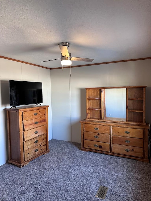 bedroom featuring dark colored carpet, visible vents, ornamental molding, a ceiling fan, and a textured ceiling