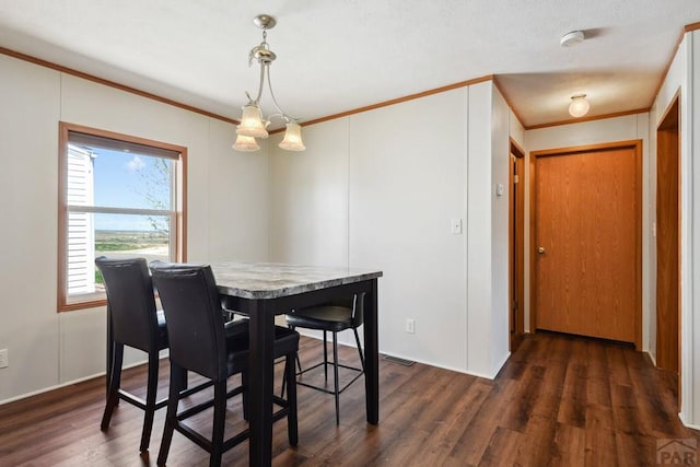 dining space with dark wood-style floors, a chandelier, and crown molding