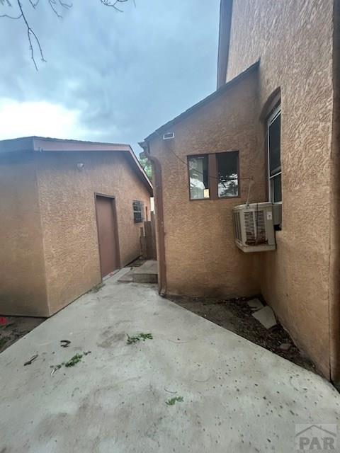 1045 Berkley Ave, Pueblo, CO 81004 - view of side of home featuring a patio area, stucco siding, and cooling unit
