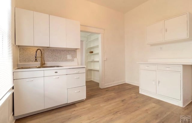 kitchen with light wood-style floors, baseboards, white cabinets, and light countertops