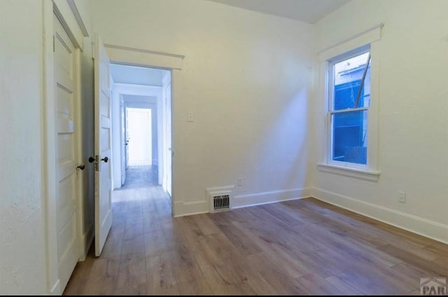 unfurnished room featuring visible vents, baseboards, and wood finished floors