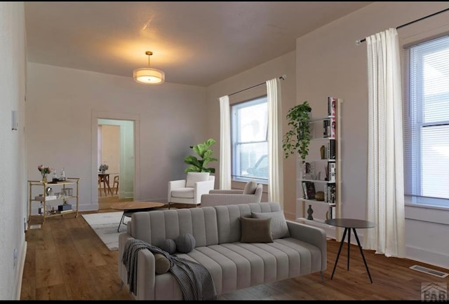 living area featuring a healthy amount of sunlight, visible vents, and dark wood-style flooring