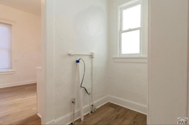 clothes washing area featuring baseboards and wood finished floors