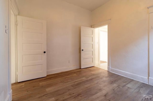 unfurnished room with baseboards and wood finished floors