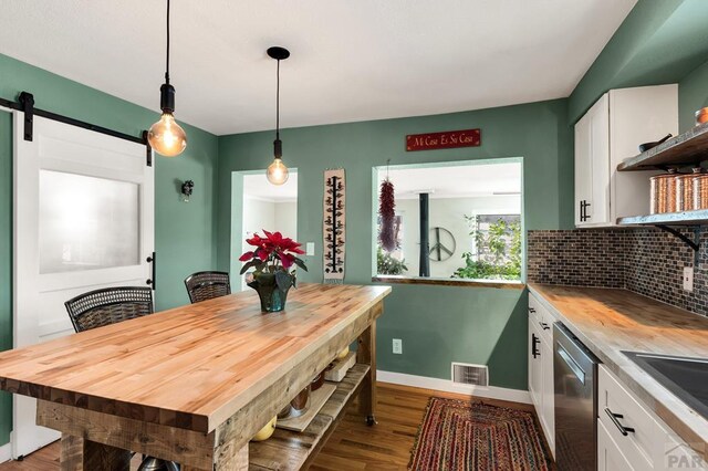 dining area featuring dark wood-style floors, a barn door, visible vents, and baseboards