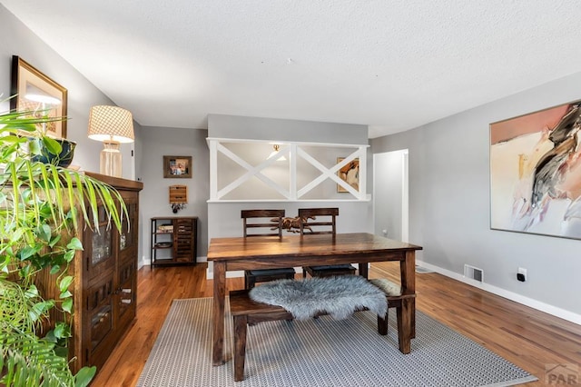 home office with baseboards, a textured ceiling, visible vents, and dark wood-type flooring