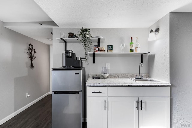 kitchen featuring a sink, white cabinetry, baseboards, freestanding refrigerator, and open shelves