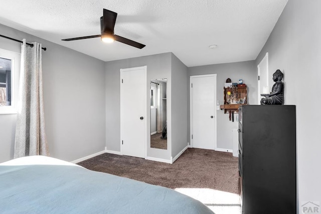 bedroom featuring a textured ceiling, ceiling fan, dark carpet, and baseboards