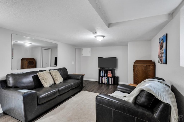 living area with a textured ceiling, baseboards, and wood finished floors