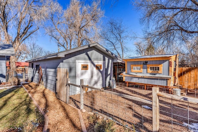 exterior space featuring driveway, fence, board and batten siding, and an outdoor structure