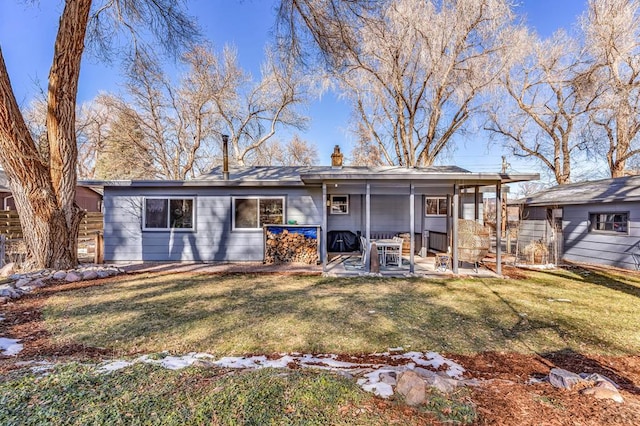 rear view of house featuring a chimney, a lawn, and a patio