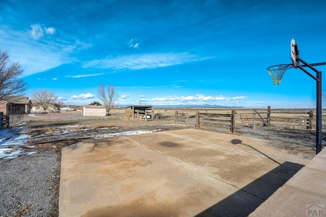 view of patio / terrace featuring a rural view, community basketball court, and fence