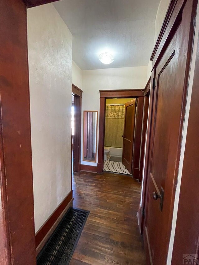 corridor with dark wood finished floors and baseboards