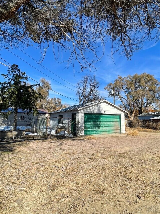 view of front facade featuring a garage, driveway, fence, and an outdoor structure