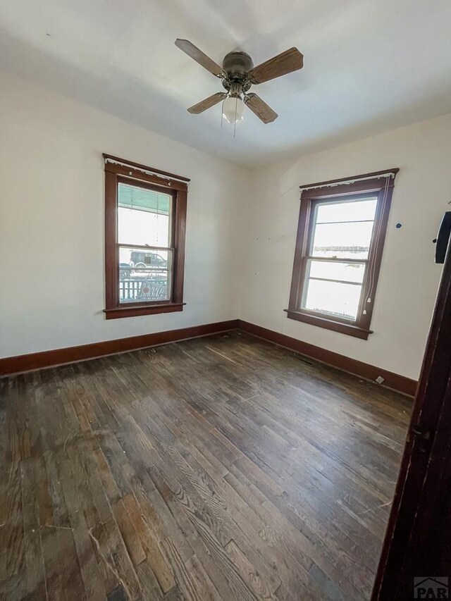 empty room with baseboards, dark wood finished floors, and a ceiling fan