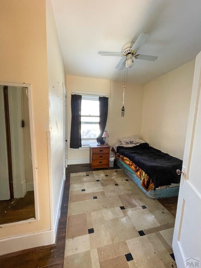 bedroom with light floors, ceiling fan, and baseboards