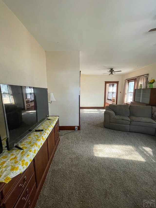 carpeted living area featuring ceiling fan and baseboards